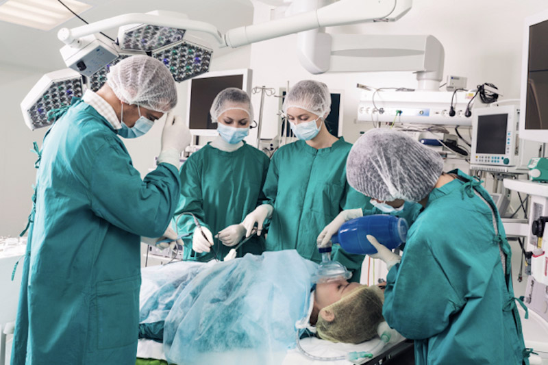 Equipe di chirurghi in sala operatoria con paziente sdraiato sul lettino anestetizzato per svolgere la biopsia