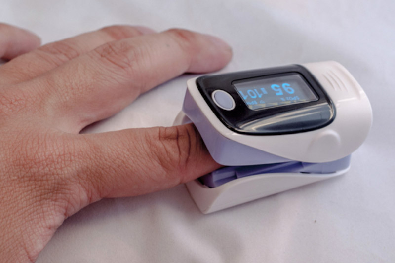 Primo piano del dito di un paziente inserito nello strumento per effettuare la pulsossimetria e misurare il livello di ossigeno nel sangue