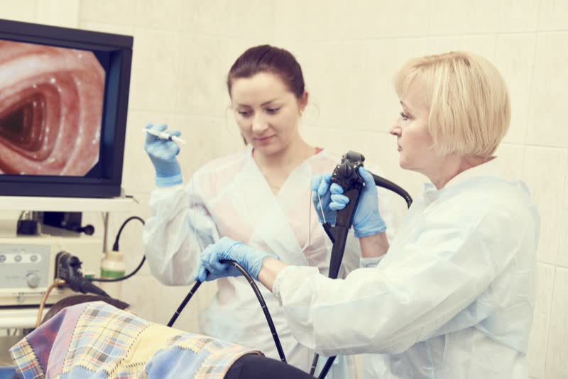 Medico e assistente nel corso di un'esame di fibroscopia su paziente disteso su lettino