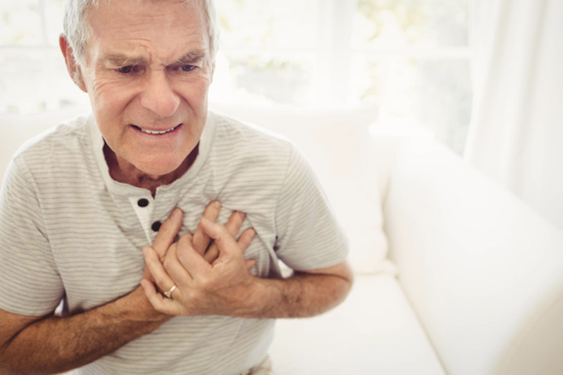 Primo piano di un uomo adulto che tiene le mani al petto per un forte dolore causato sall'infarto