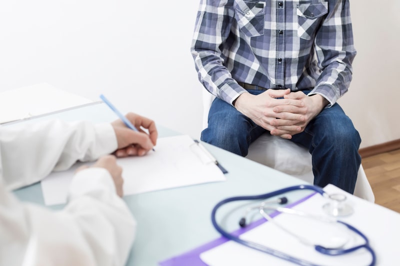 Uomo seduto in un ambulatorio mentre parla con un medico per il problema di disfunzione erettile 