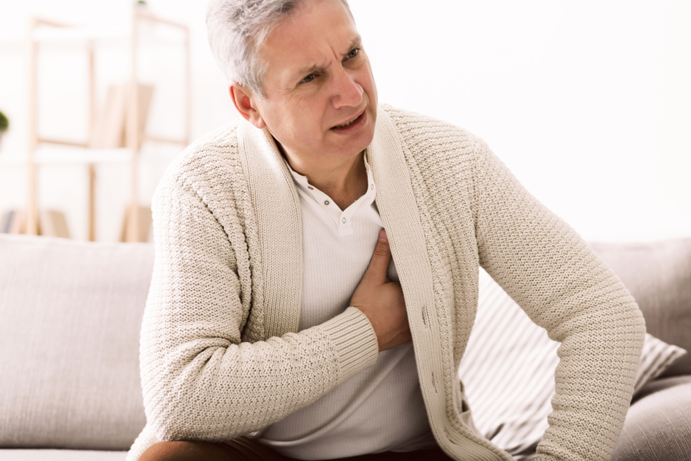 Uomo sofferente si tiene le mani al petto a causa del cuore polmonare cronico