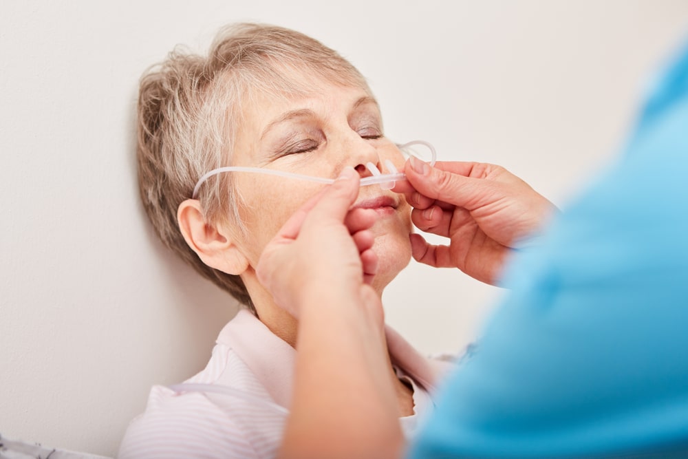 Donna adulta viene aiutata da un medico a inserire nel naso dei tubi di supporto per la respirazione a causa della BPCO