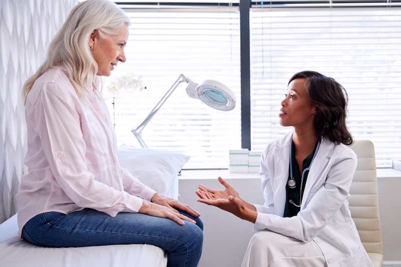 Paziente donna seduta su un lettino di uno studio medico mentre parlare con il duo dottore riguardo la caruncola uretrale