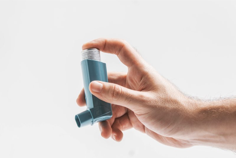 Primo piano della mano di un uomo che tiene un farmaco broncodilatatore per curare l'asma grave 