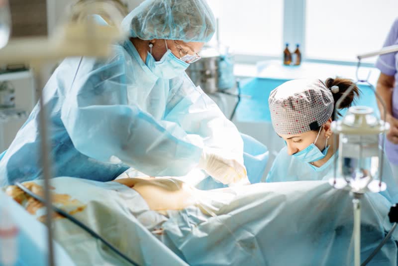Equipe di chirurghi ginecologi che operano una paziente donna di uretrocele