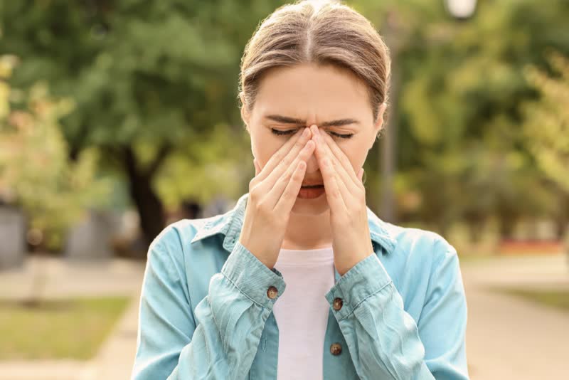 Foto di donna con le mani sul naso colpita da un attacco allergico per colpa della sua allergia