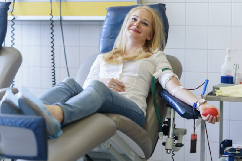 Donna seduta su un lettino di ospedale mentre esegue un prelievo del sangue 