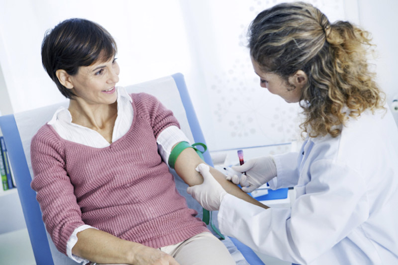 Paziente donna in una sala di un centro trasfusionale esegue un prelievo del sangue fatto da un'infermiera