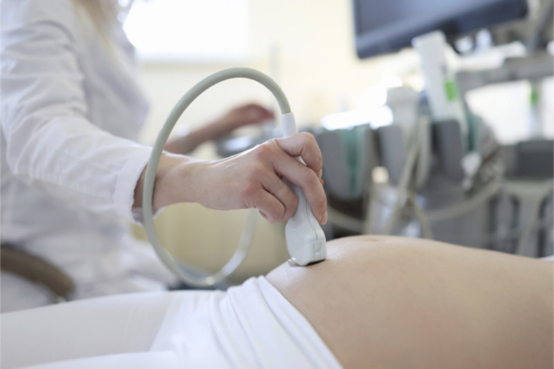 Medico che esegue l'esame ecografico di una donna incinta in primo piano 