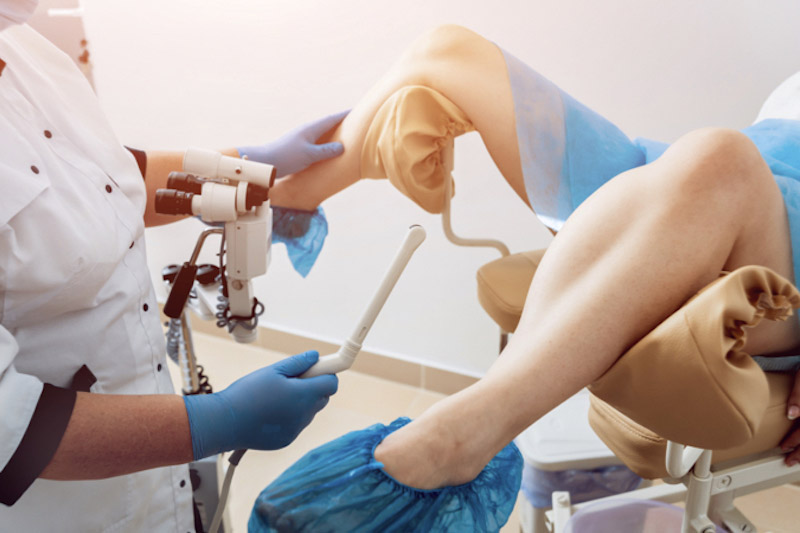 La ginecologa usa l'ecografo per eseguire una isterosonografia su una paziente seduta sulla poltrona con gambe divaricate