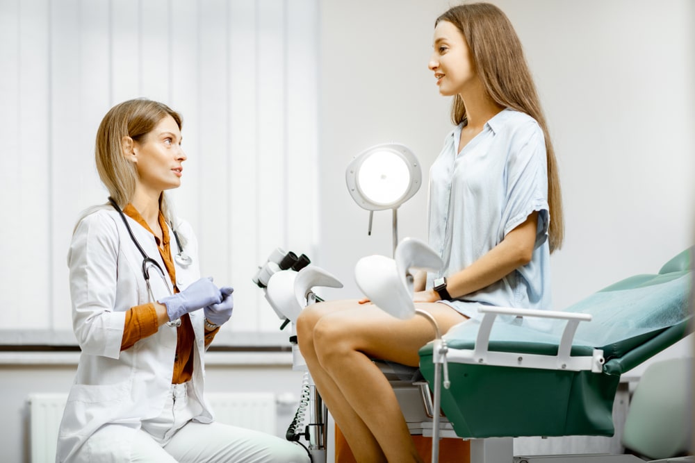 Paziente donna seduta su un lettino di una sala medica mentre parla con la ginecologa prima di effettuare il monitoraggio follicolare