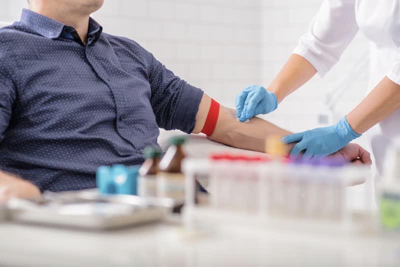 Primo piano di un infermiere che disinfetta il braccio di un uomo prima dell'esame del sangue (esami ematochimici)