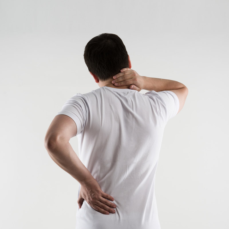 Uomo di schiena pone le mani sulla parte posteriore del collo e della schiena a causa di dolori localizzati per cordoma