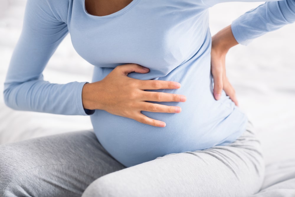 Primo piano di una donna in gravidanza con mal di schiena e crampi a causa dell'incontinenza cervicale