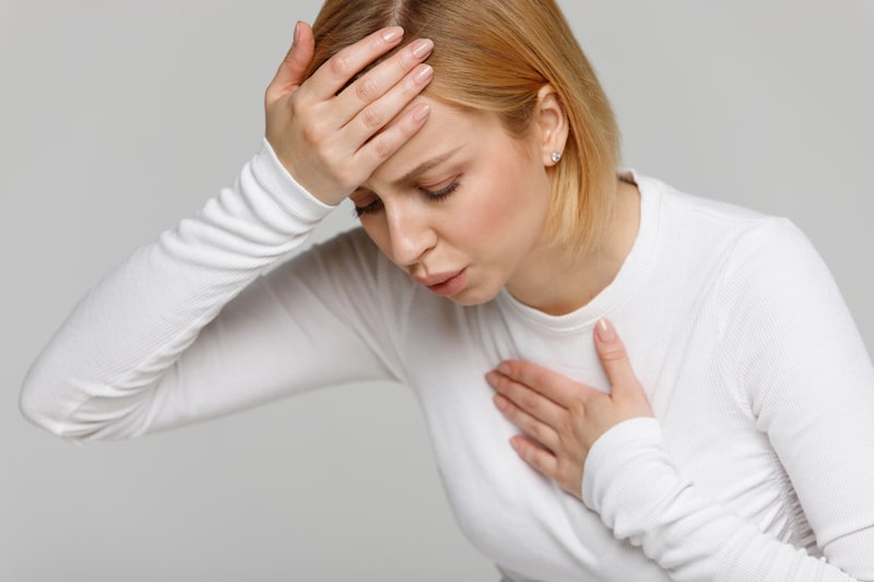 Primo piano di una donna con mani al petto e in testa fa fatica a respirare a causa del broncospasmo