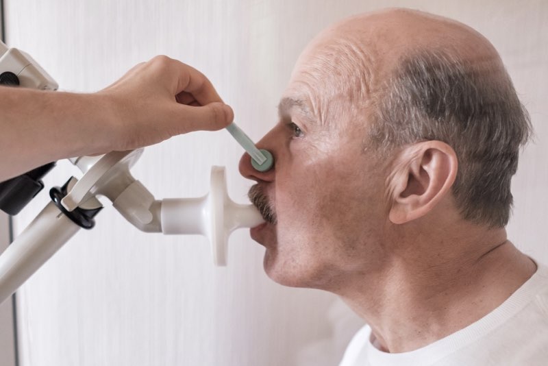 Primo piano di un uomo adulto mentre esegue la spirometria per diagnosticare l'asma grave