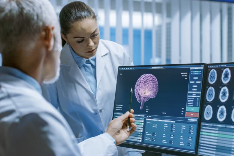 Equipe di medici di fronte ad uno schermo con i risultati di una tomografia computerizzata (TC) cerebrale su un paziente affetto da ganglioneuroma