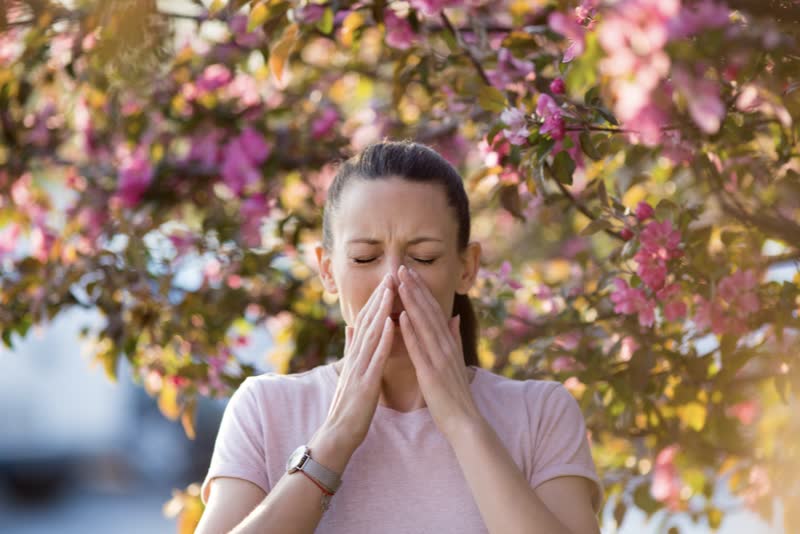 Foto di donna con mani sul naso perché soffre di asma allergica