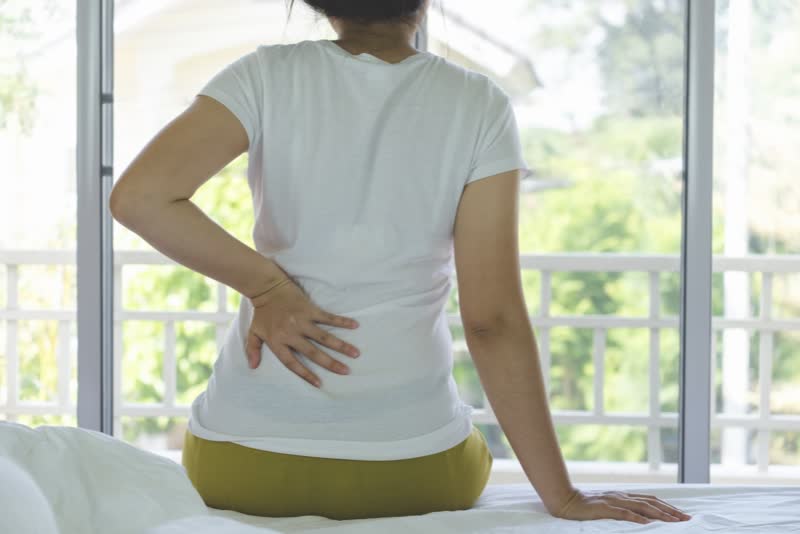Foto di donna con mano sulla schiena sofferente a causa di nsufficienza renale
