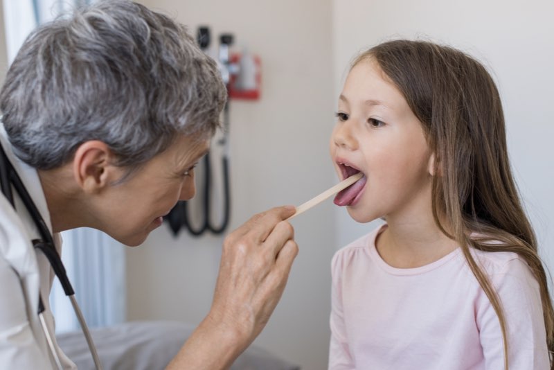 Fotografia di una dottoressa che visita una bambina per controllare le tonsille a seguito dell'intervento di tonsillectomia