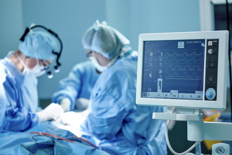 Equipe medica di chirurghi cardiologi all'interno di una sala operatoria tappezzata di blu nel corso di un intervento di valvuloplastica
