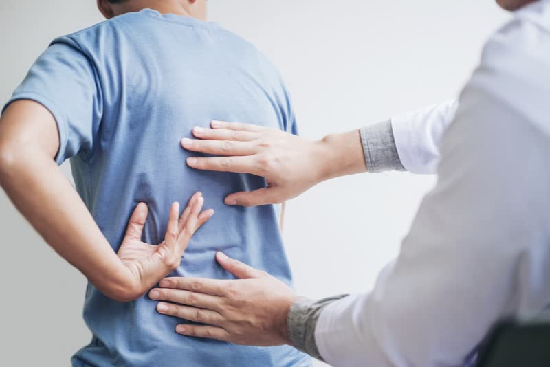 Medico o dottore che consulta un paziente con problema alla schiena per effettuare una terapia del dolore